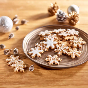 Snowflake cookies on a plate with Christmas decorations on a wooden surface