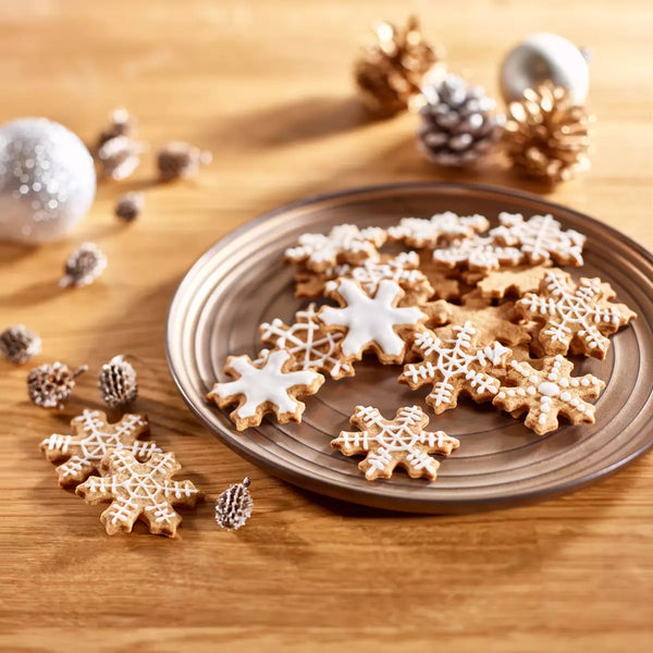 Snowflake cookies on a plate with Christmas decorations on a wooden surface