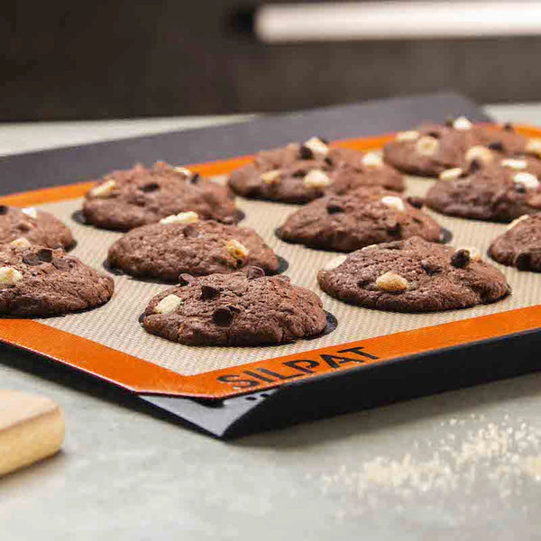 Chocolate cookies on a Silpat baking mat with a blurred kitchen background