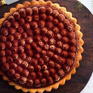 Berry tart on a wooden board with a white background
