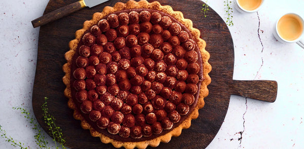 Berry tart on a wooden board with a white background