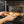 Person placing a pizza on a stone into an open oven.