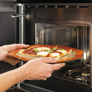 Person placing a pizza on a stone into an open oven.